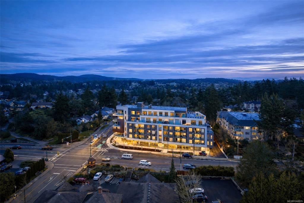 Aerial view of a new condo building and Greater Victoria neighbourhoods at dusk